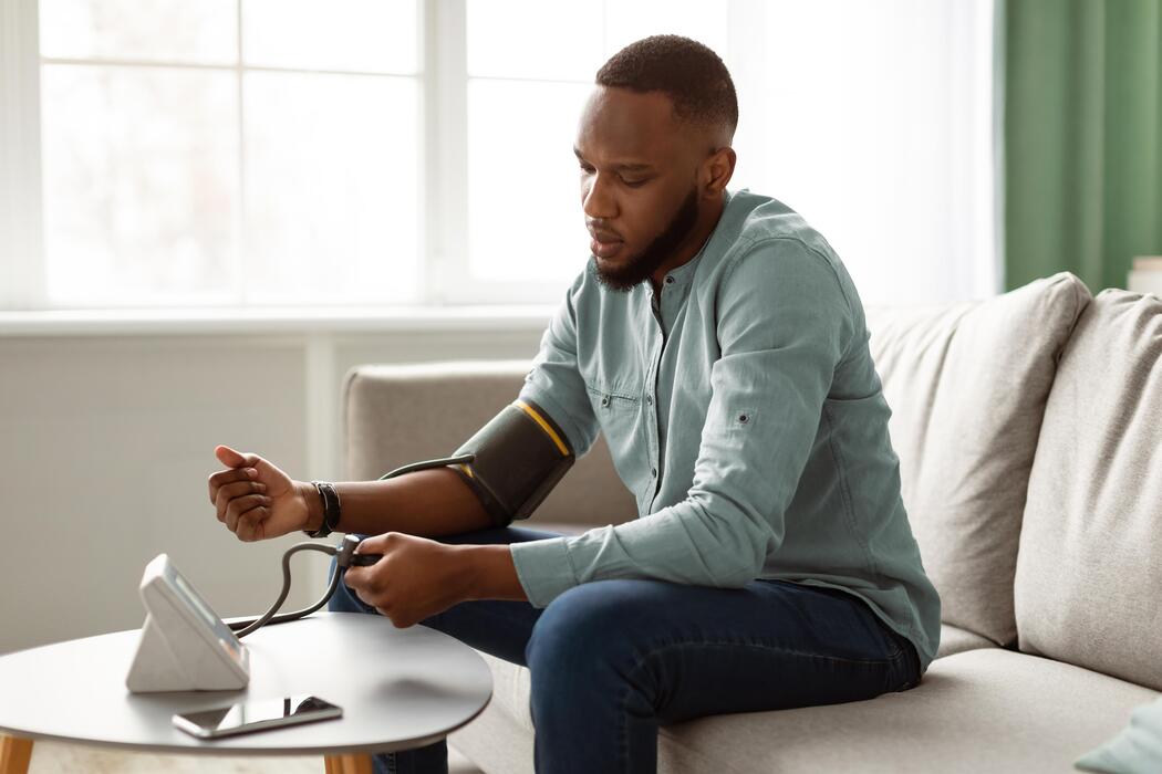 Young Nigerian man checking his blood pressure with a home monitor